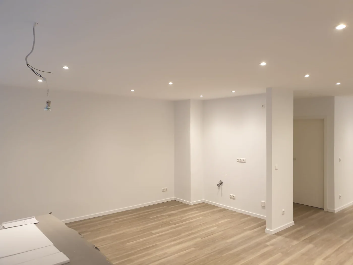 Fertig ausgebauter Wohnraum mit neuem Holzboden, verkleideter Stütze und eingelassenen Deckenspots